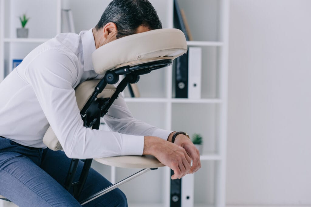 businessman sitting in massage chair at office. About to start his Tulsa chair massage