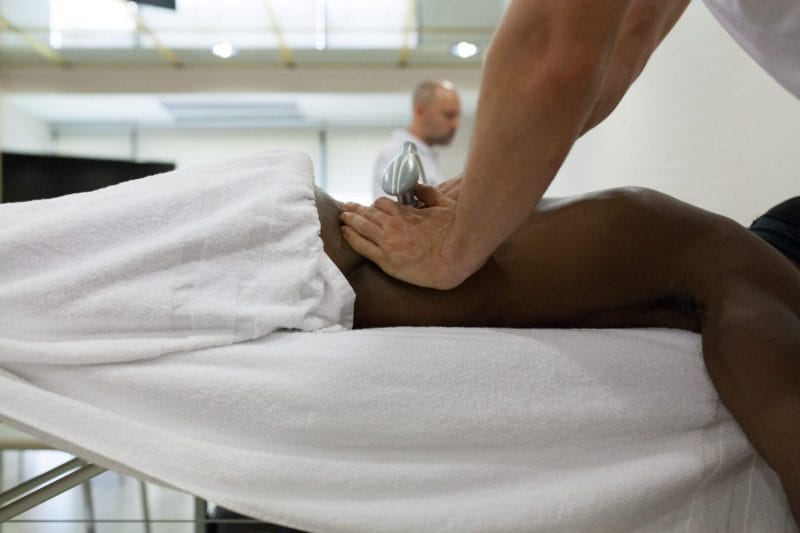 Tulsa Sports Massage | Medical Massage of Tulsa therapist applying back massage to young black Tulsa man lying face down on stretcher